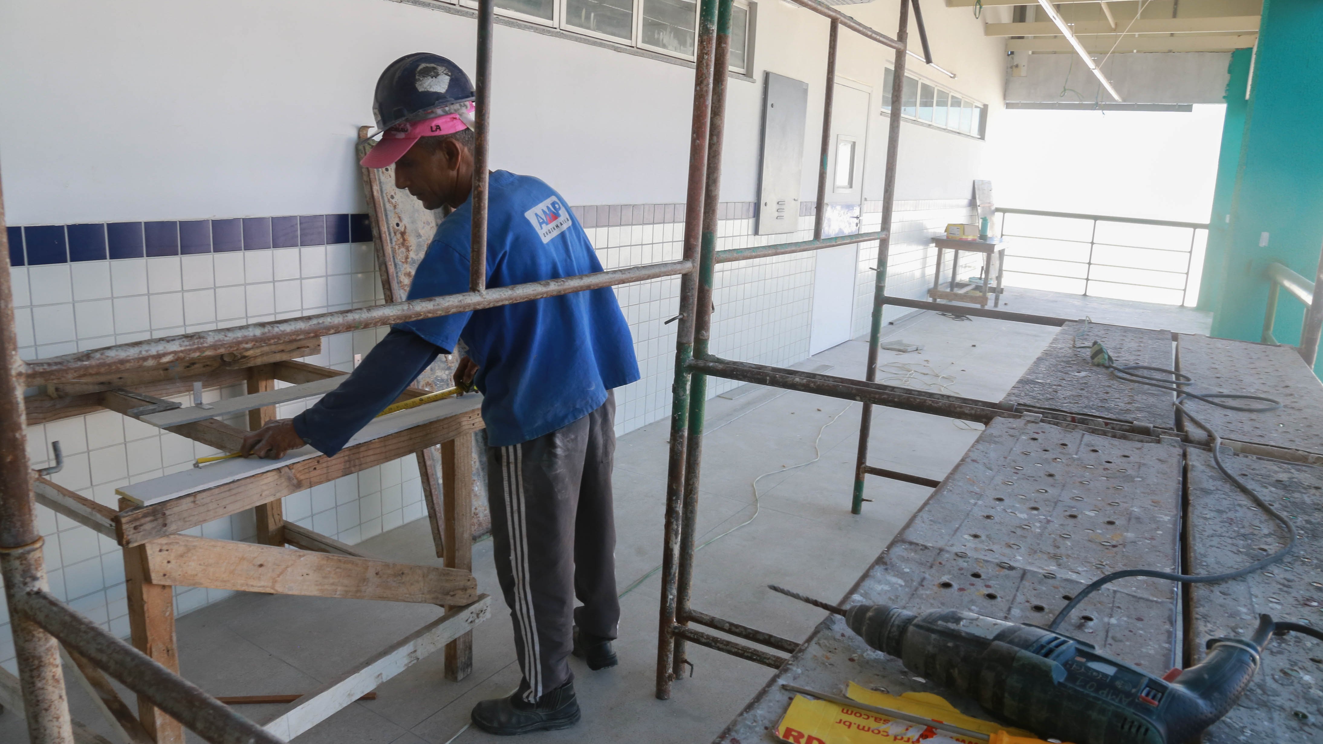 operário mede um pedaço de madeira em um corredor em obras